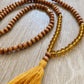 amber glass beads, wooden beads, and a mustand cotton tassel