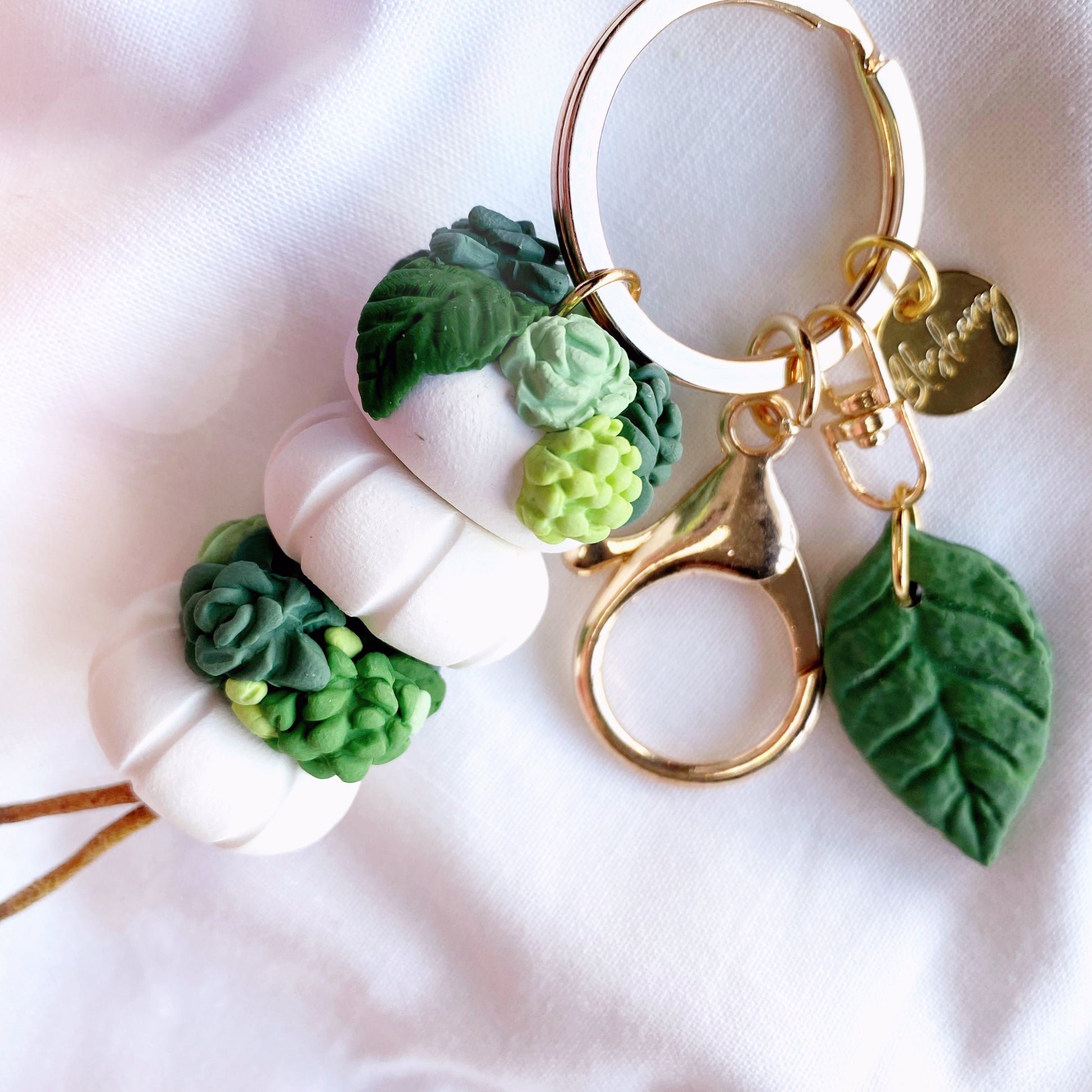 small white clay beads, draped with green plants leaves and succulents, with a leaf charm
