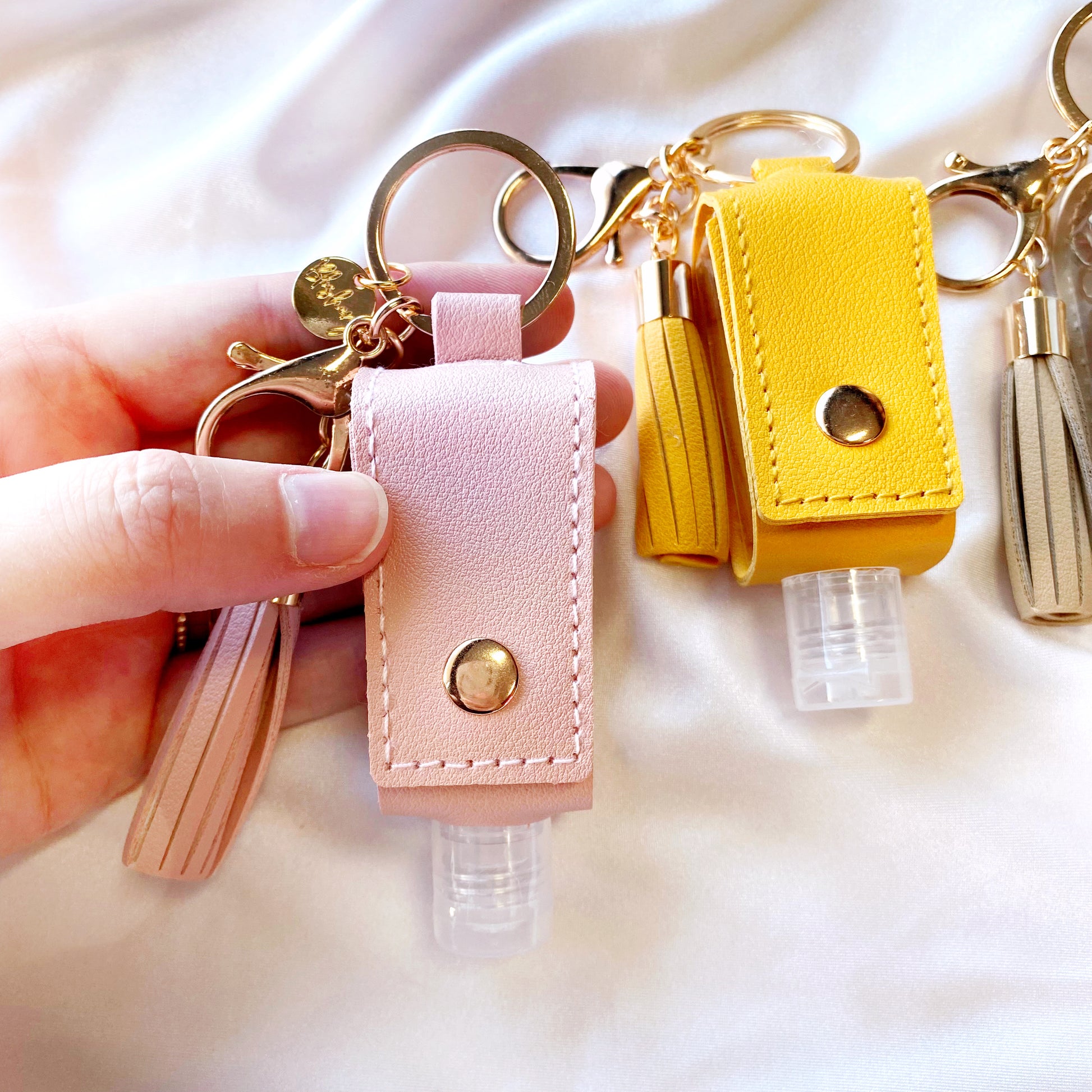 small hand sanitiser bottle holders with a tassel and keychain