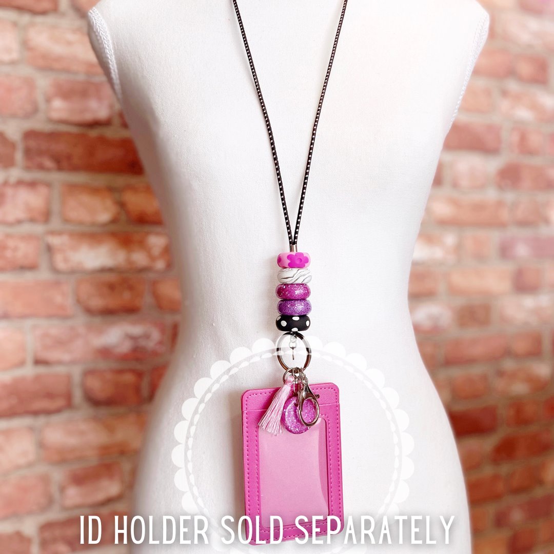the pink and purple polymer clay beaded lanyard on display model with id holder and whistle