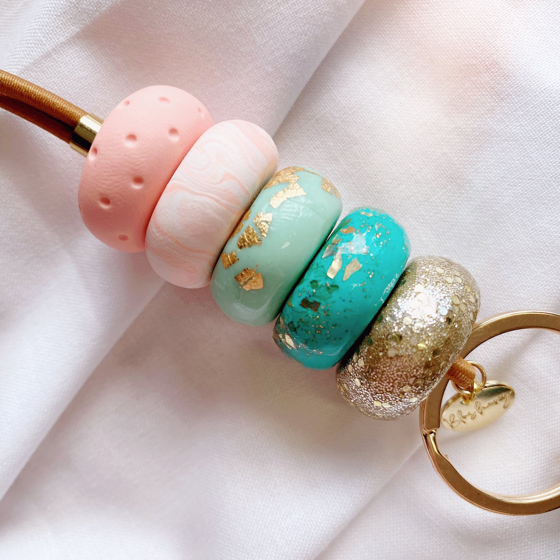 up close to the peach and teal and mint polymer clay beads, with gold glitter and marble print