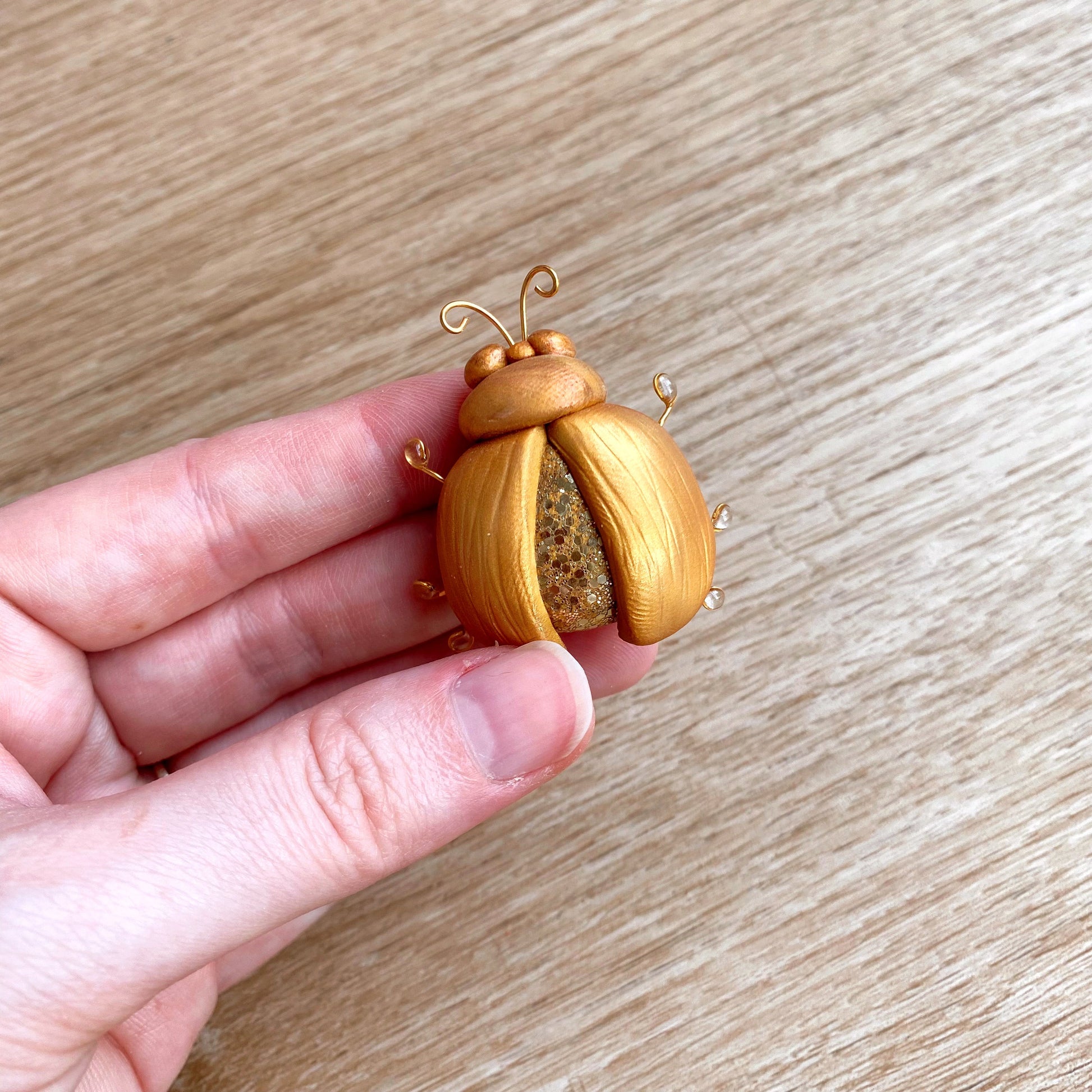 hand sculpted polymer clay brooch in traditional gold beetle design