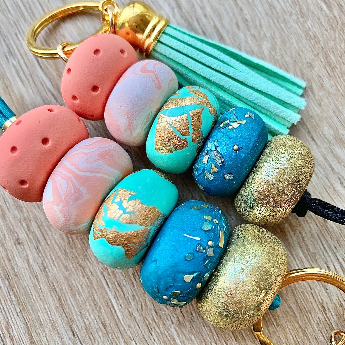 clay beads with gold glitter, peach marble and gold leaf, with a mint tassel